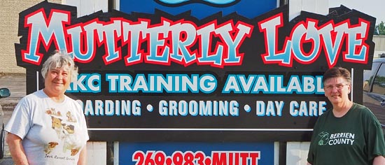 Two women standing in front of the Mutterly Love sign.